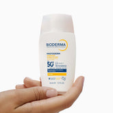 Bioderma sunscreen bottle held in a hand on a white background